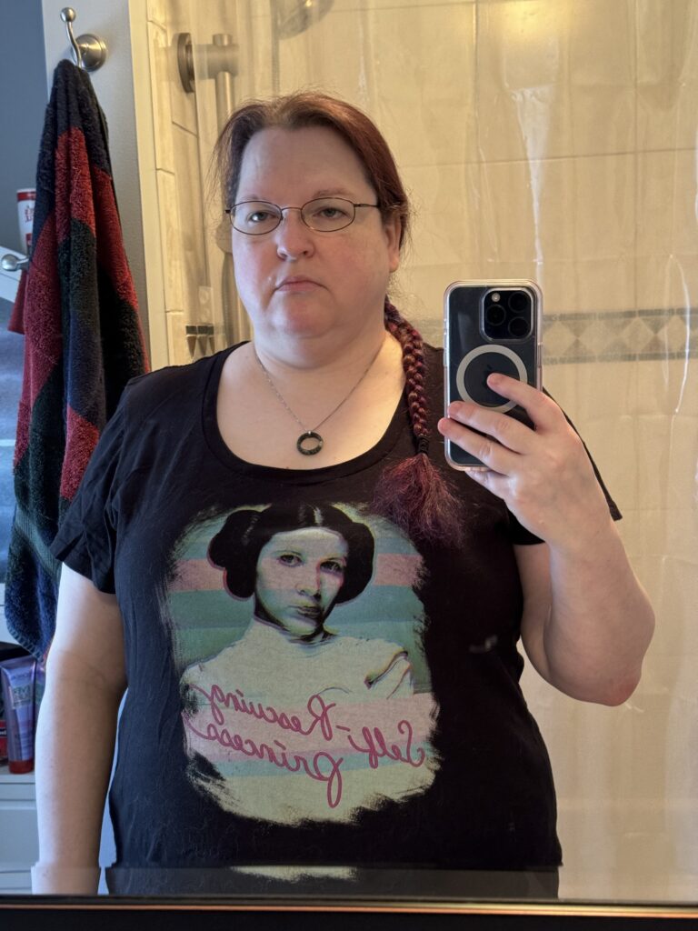 A mirror selfie of the same woman, wearing the same shirt, with purple-ish hair in a braid over her shoulder. There's no difference in her appearance.